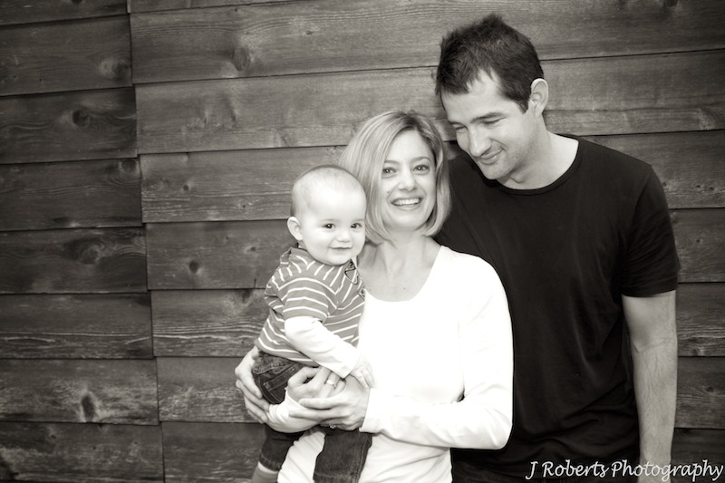Sepia family of 3 in front of wooden shed - family portrait photography
